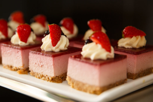 Close up of pink desserts with strawberry and cream on a plate